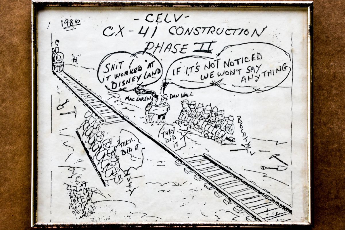 A bit of Space Program whimsy, drawn by an Air Force Safety contractor who's first name was Frank, but who's last name sadly is not remembered, depicting interagency rivalry, as well as intra-program rivalry, showing James MacLaren (site representative for Ivey Steel during the Complex 41, Titan IV tearout and refurbishment phase of converting Pad 41 from Titan III functionality to Titan IV functionality) puzzling over a blueprint along with Dan Wall (Martin Marietta site representative). 'Disney Land' is an uncomplimentary epithet for NASA, which was uniformly held in contempt by everyone on the Air Force side of America's Space Program, and refers to MacLaren's previous tenure, working for NASA at Space Shuttle Launch Complex 39-B. The misaligned train tracks represent the railway, and subterranean heavy-concrete support for it, over which the Mobile Service Tower at Pad-41 traveled across, part of which was furnished and installed by the Bechtel Corporation, and the other part of which was furnished and installed by Ivey Steel, which two parts fictionally fail to properly match for dramatic effect, and which neither the contractors, Martin Marietta, nor the Air Force, are willing to take responsibility for, which was ever so non-fictionally typical for any and all situations of this type that cropped up during the course of the work.